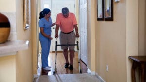 Nurse helping man with walker